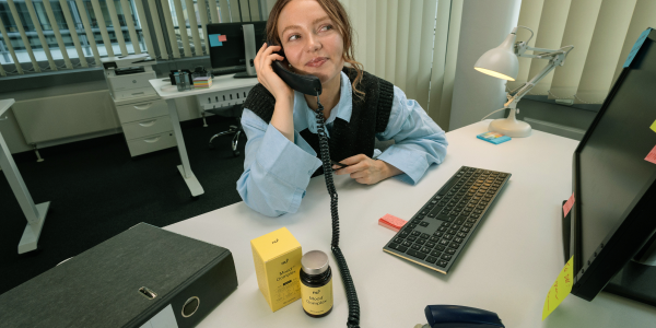 Donna in ufficio che parla al telefono con il nu3 Mood Complex sulla scrivania