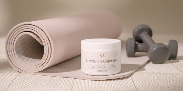 nu3 L-Arginina su tappetino di allenamento con manubri