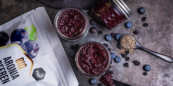 nu3 Bacche di aronia giacciono accanto a marmellata e frutti di bosco freschi