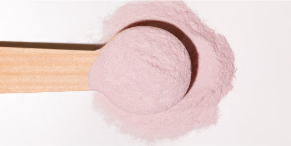 Polvere rosa su un cucchiaio di legno