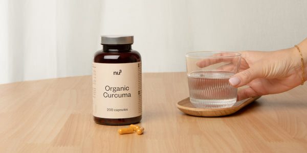Curcuma bio con capsule e bicchiere d'acqua