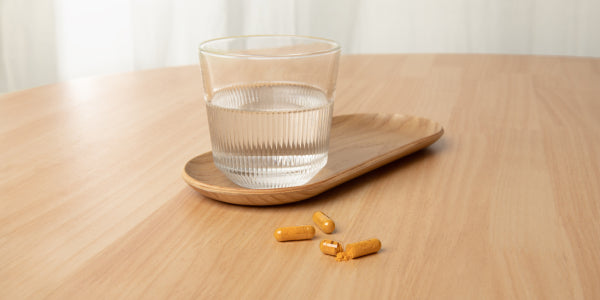 Capsule di curcuma bio e bicchiere d'acqua
