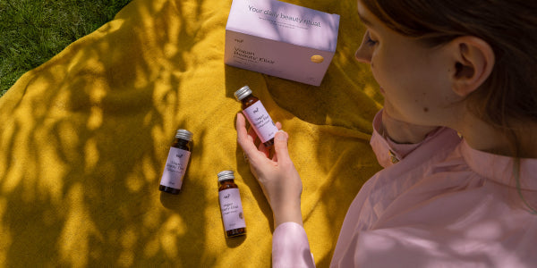 Donna con Vegan Beauty Elixir nel parco su una coperta gialla