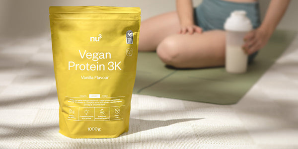 Vegan Protein 3K gusto vaniglia di fronte a un atleta su un tappetino da fitness