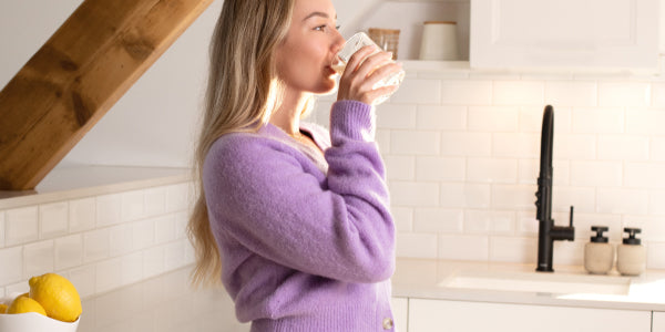 Donna che beve un frullato in cucina