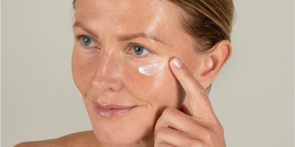 Donna con bella pelle e crema per il contorno occhi