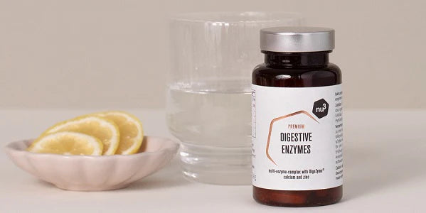 Confezione di enzimi digestivi con bicchiere d'acha e fette di limone