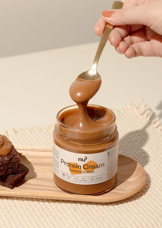 nu3 Protein Cream Salted Caramel auf einem kleinen Holzbrett, daneben ein Brownie