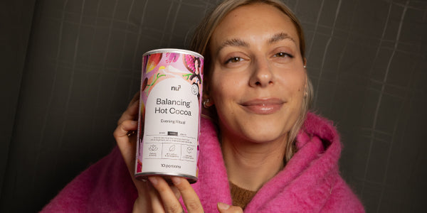 Donna felice con un barattolo di nu3 Balancing Hot Cocoa