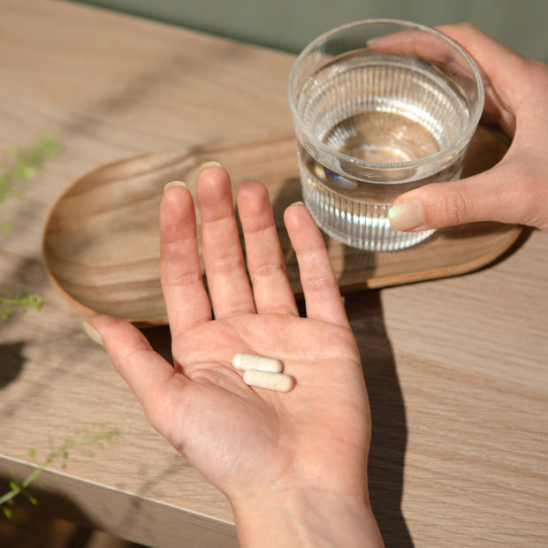 Capsule in mano con un bicchiere