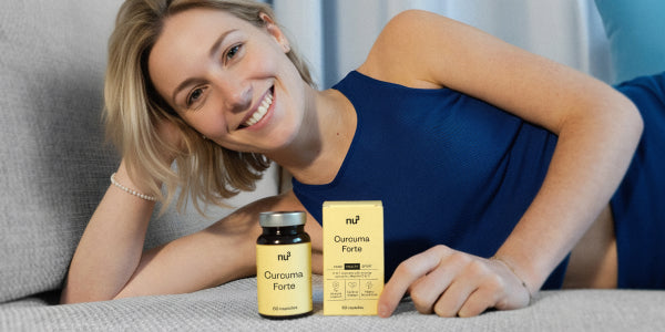 Giovane donna in top blu sdraiata sul divano con nu3 Curcuma Forte